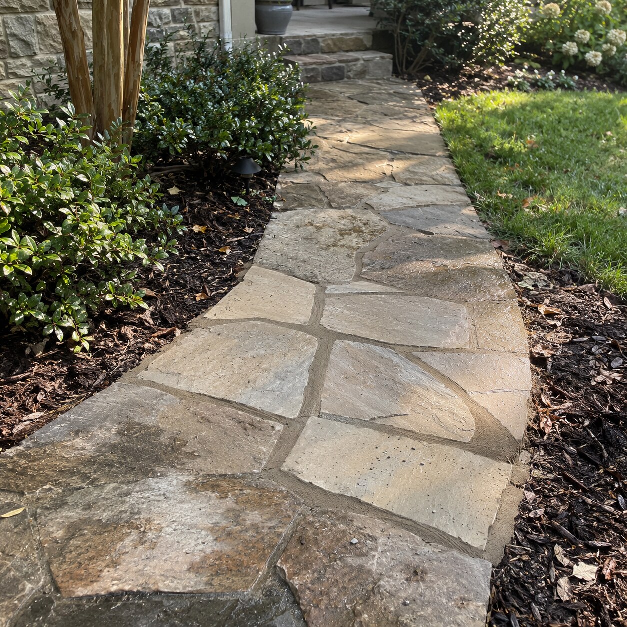 A flagstone walk reset and pointed, curving between mulched beds to the front steps.