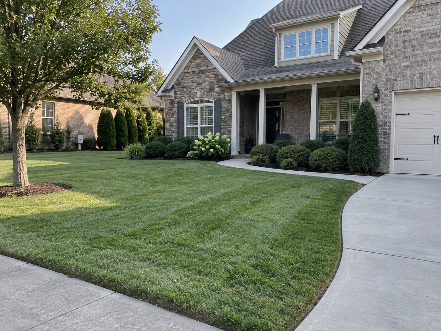 A brick front yard in ordinary kept condition — clean mow lines, crisp bed edges, nothing that needs doing.